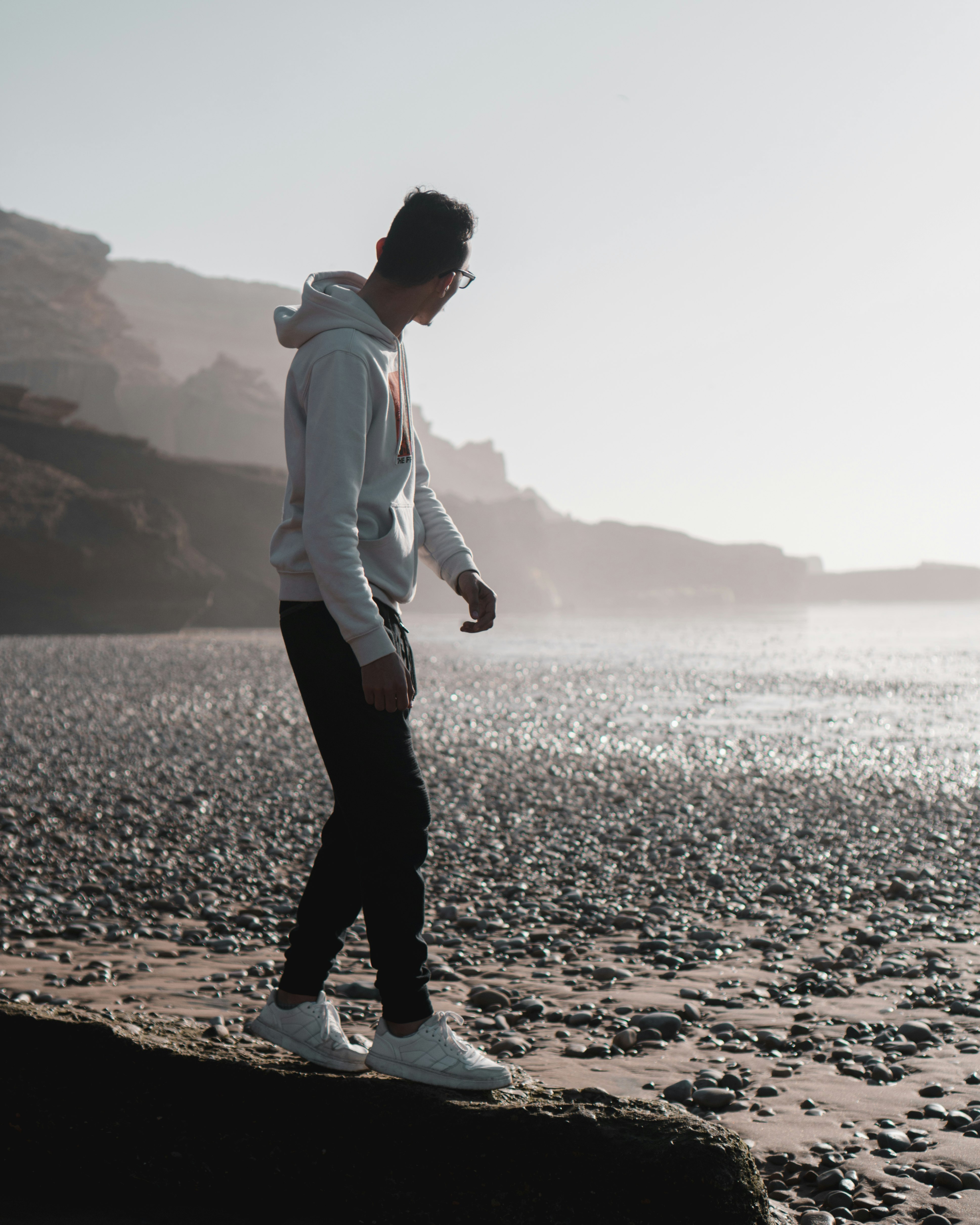 man in white dress shirt and black pants standing on brown sand during daytime